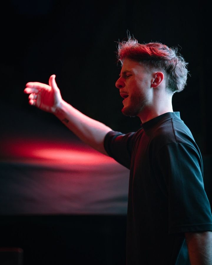 YOUNGS de profil, bras tendu sous une lumière rouge